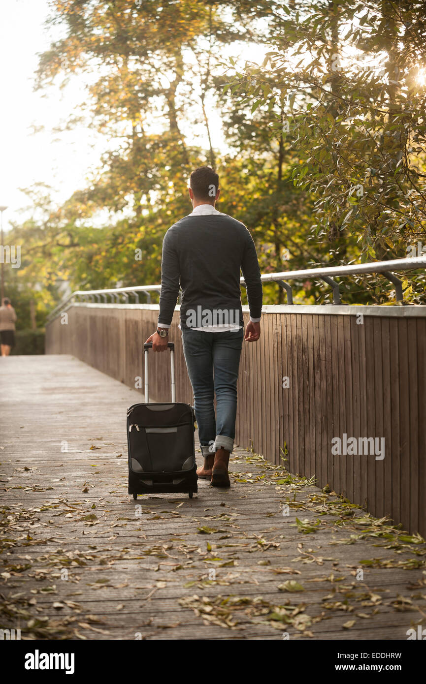 Joven caminando con sus maletas con ruedas sobre un puente peatonal  Fotografía de stock - Alamy