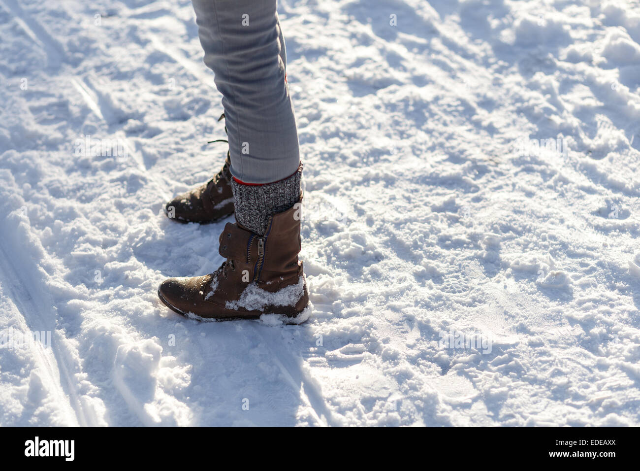 Las piernas de chica delgada en botas de luz en la nieve del invierno. Foto de stock