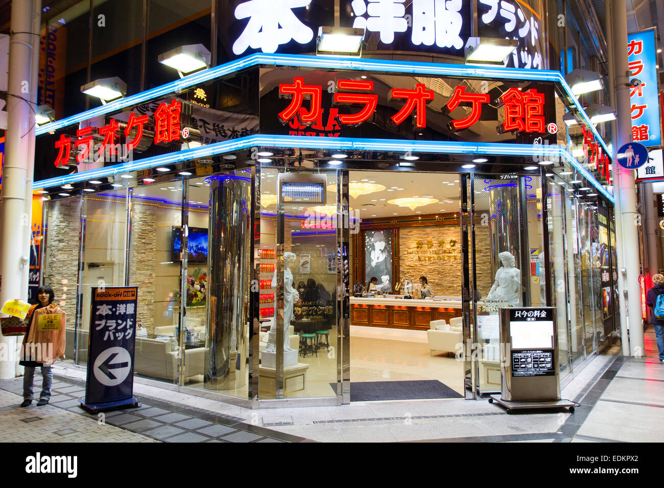 La esquina de cristal de la tienda de Karaoke, Karaoke Ken en la galería comercial de Dotonbori en Osaka, Japón. Vista desde fuera mirando hacia adentro. Noche. Foto de stock