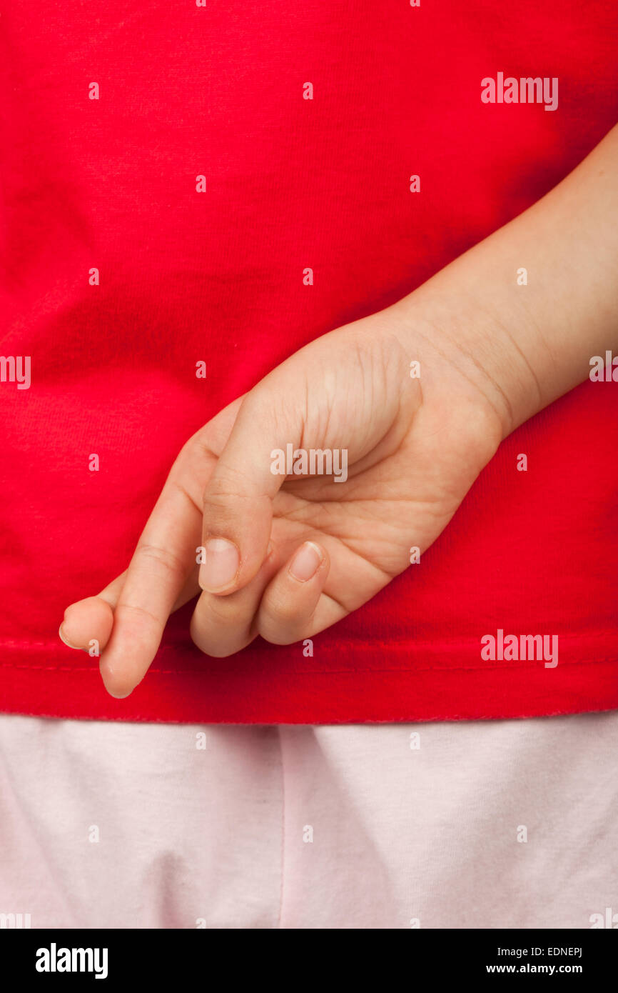 Niño con los dedos cruzados detrás de su espalda para excusar diciendo una mentira Foto de stock