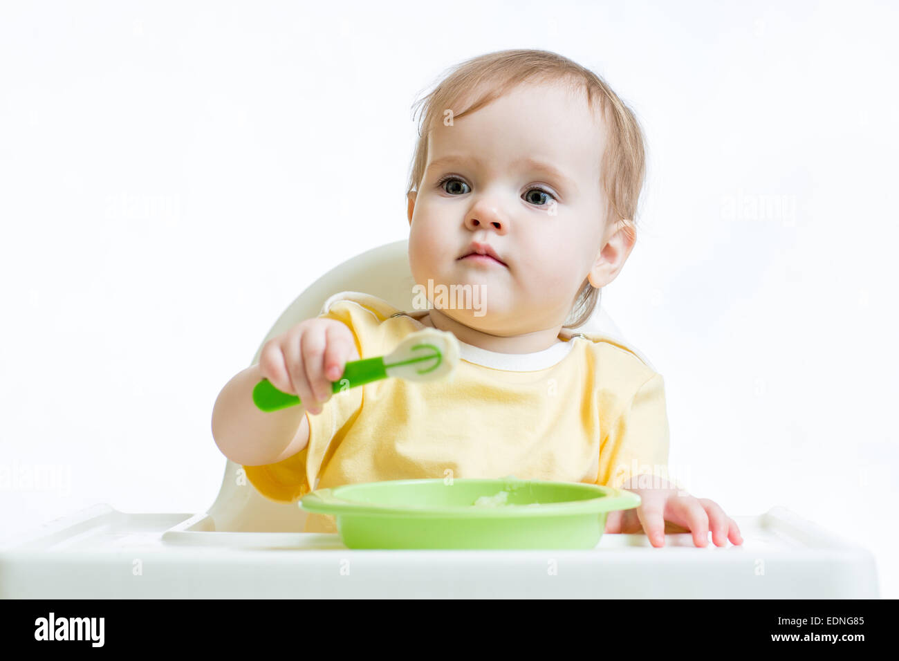 Bebé niña sentada en una silla con una cuchara Foto de stock