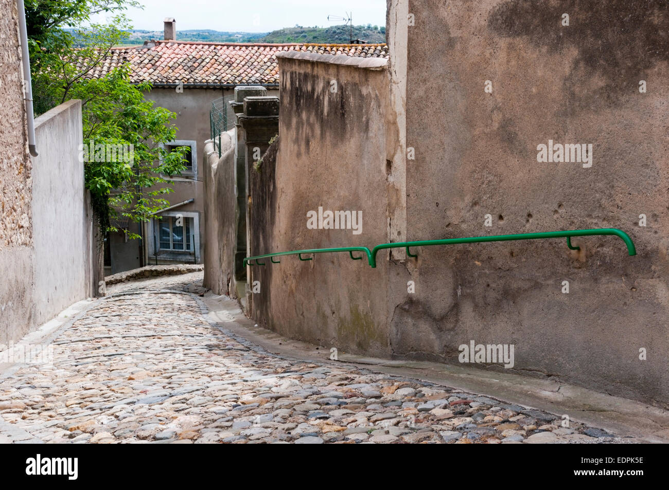 Una empinada calle adoquinada con un pasamanos en la pequeña aldea de Puissalicon, Languedoc, Francia. Una histórica circulade village. Foto de stock