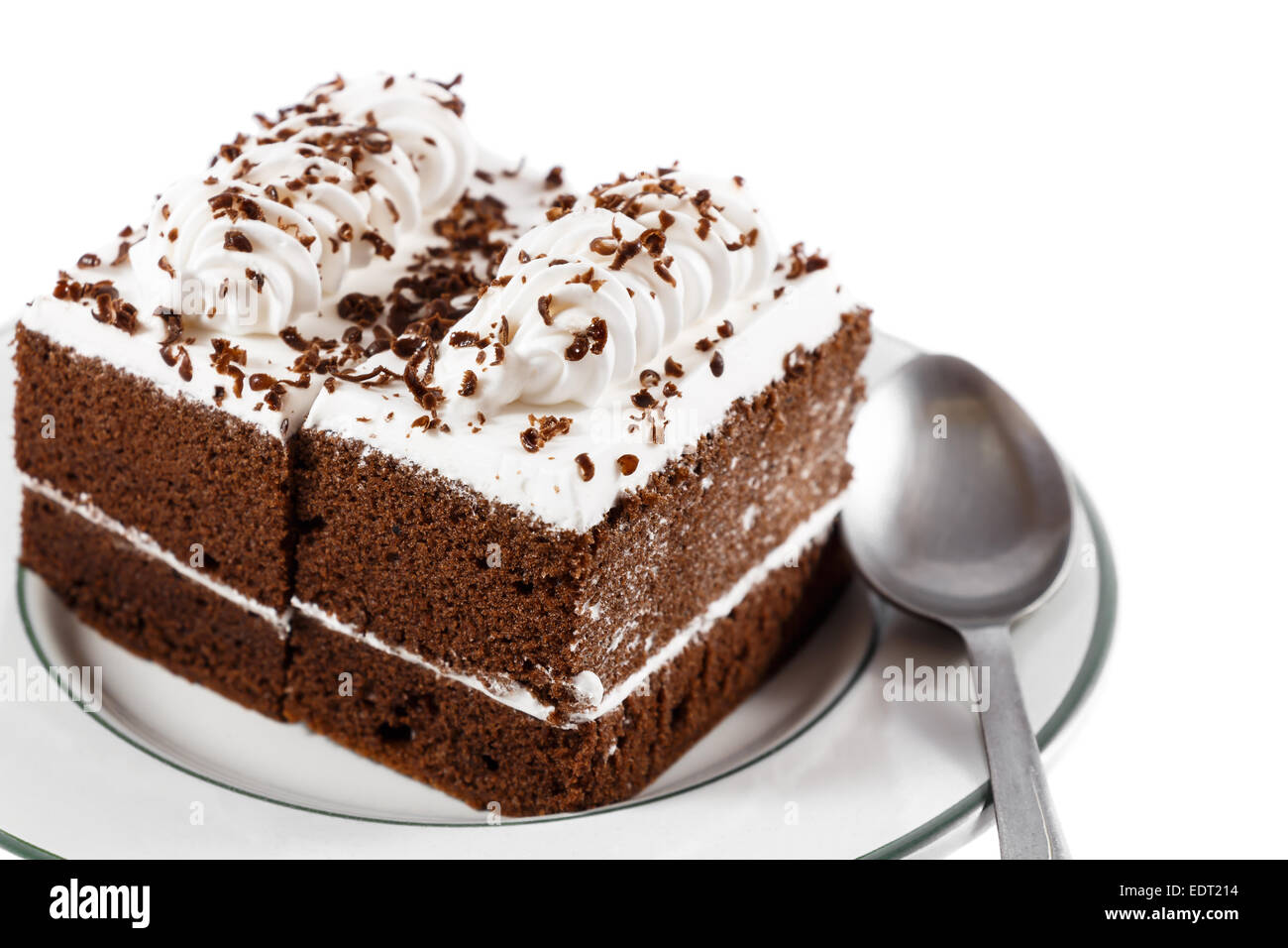 Pasteles de chocolate con crema blanca en la parte superior y una cuchara en la placa de fondo blanco(aislado) y el área en blanco en el lado derecho Foto de stock