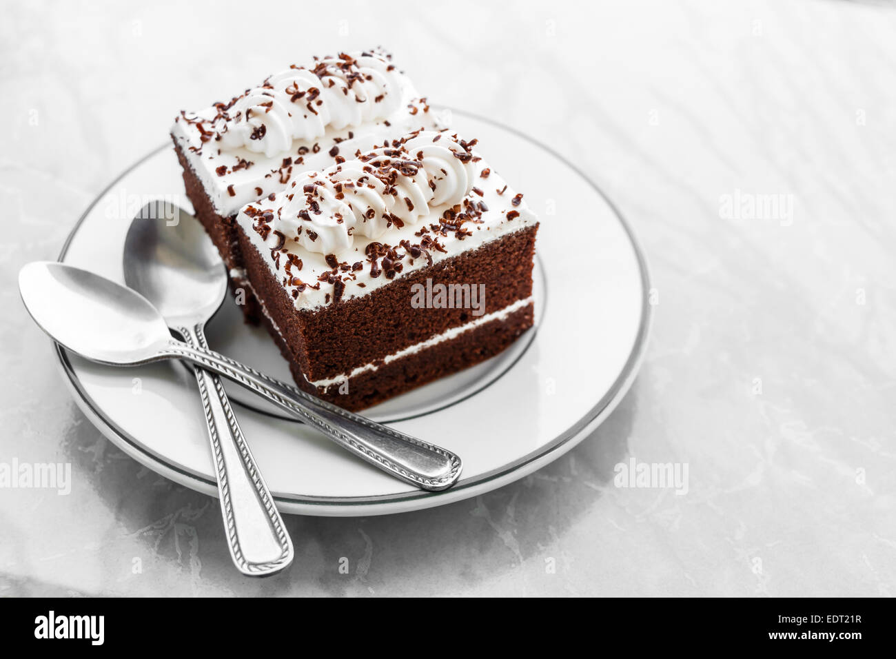 Vintage Style pasteles de chocolate con crema blanca en la parte superior y las cucharas en la placa sobre la mesa de mármol y zona en blanco en el lado derecho Foto de stock