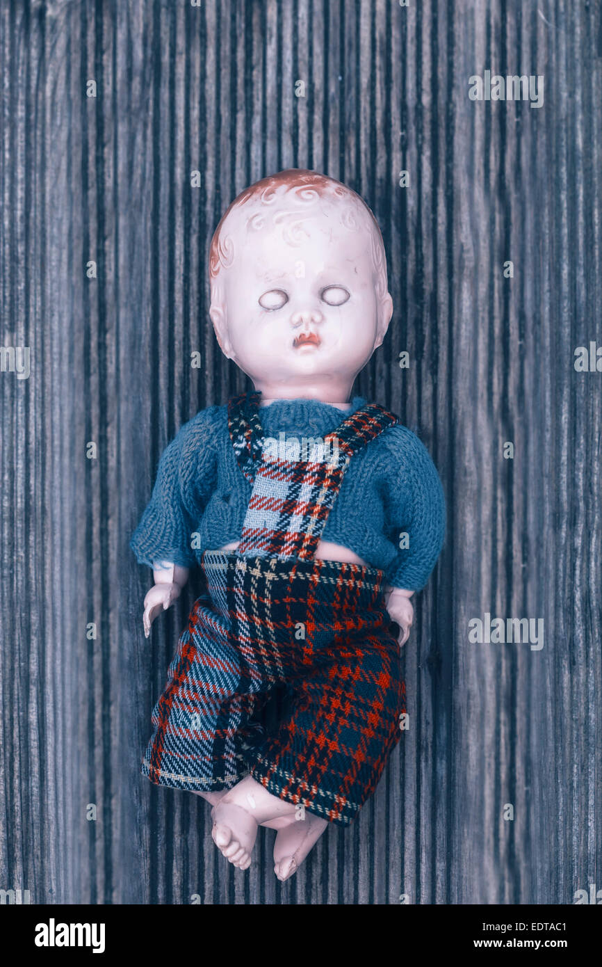 Una muñeca rota sobre un piso de madera Foto de stock