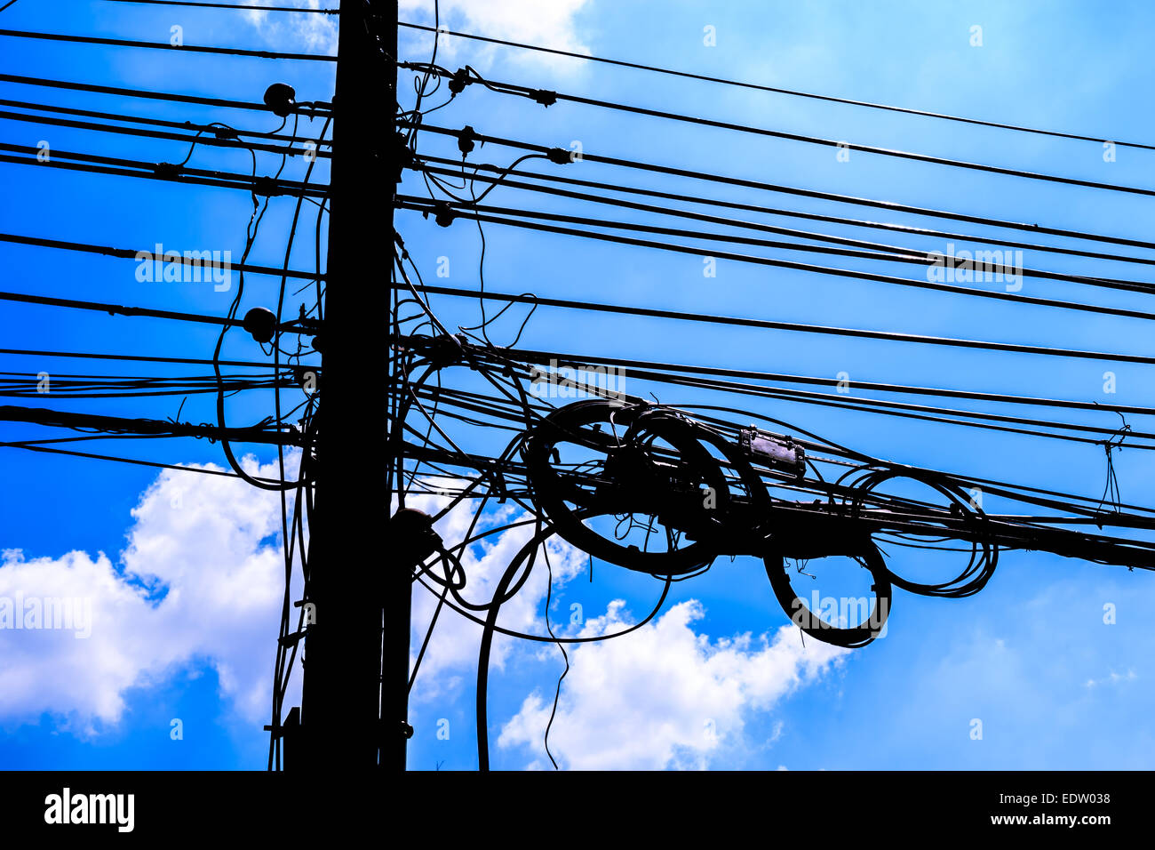 Poste de electricidad con cables desordenados y blue sky (silueta) Foto de stock