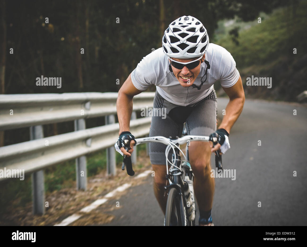 Ciclista en esfuerzo máximo en una carretera en el exterior Foto de stock