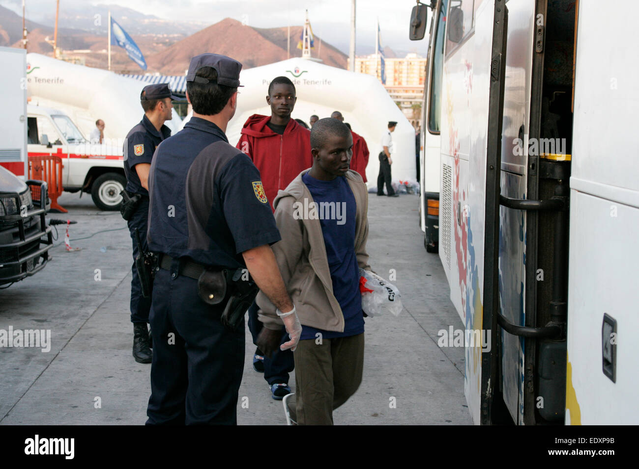 Escolta de la policía española los inmigrantes africanos ilegales para el centro de procesamiento de Los Cristianos, Tenerife, Islas Canarias Foto de stock