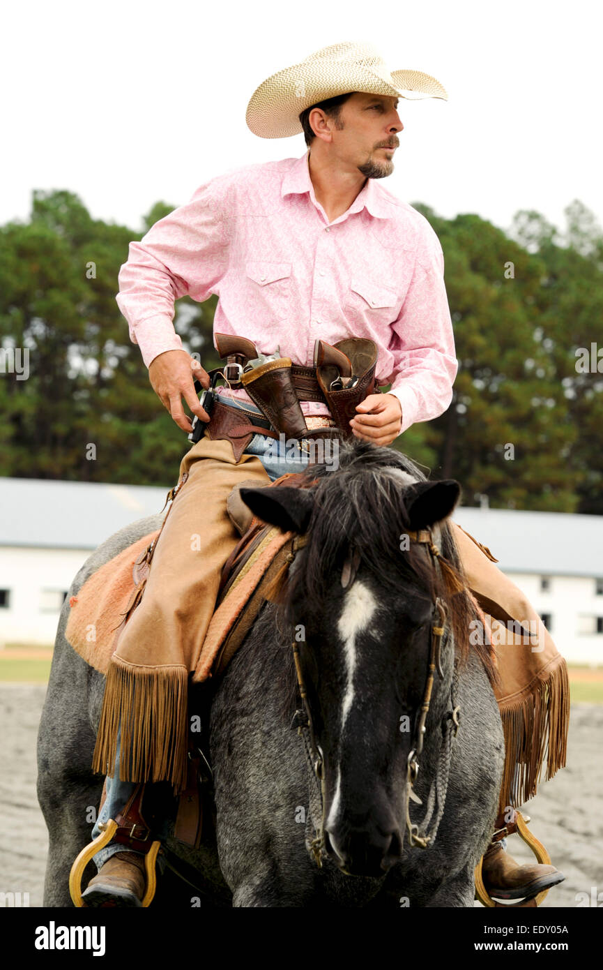 Hombre montando un caballo gris pistolas en la funda a la feria granero y pista en pinehurst Carolina del Norte Foto de stock