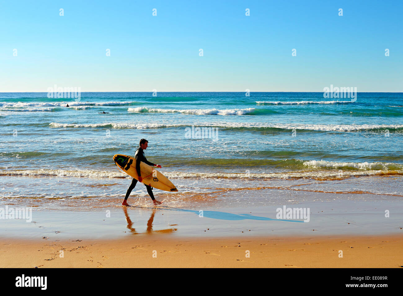 Surfer no identificadas caminar en la playa. Foto de stock