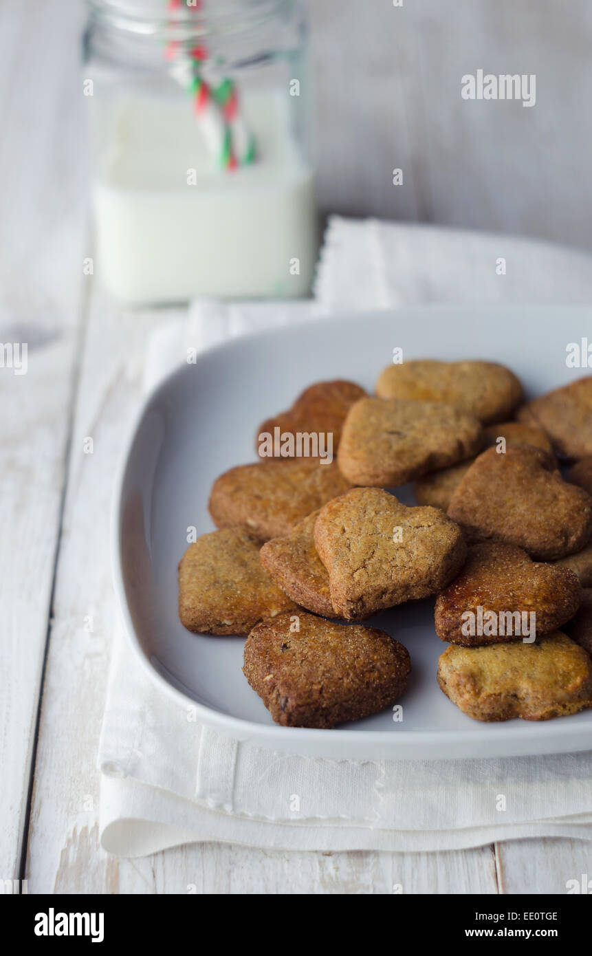 Caseras galletas en forma de corazón, sobre mesa de madera blanca Foto de stock