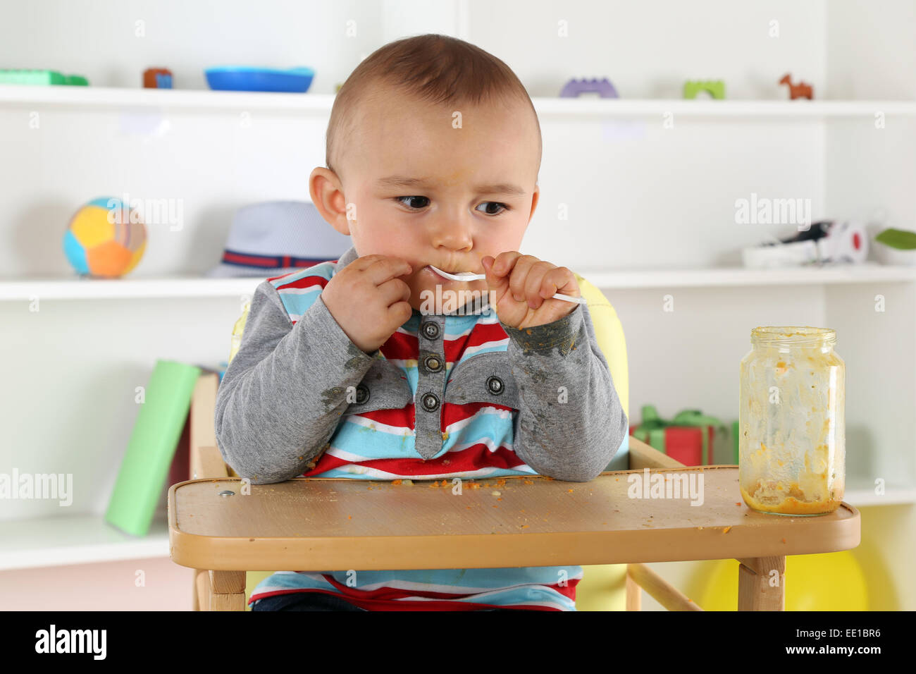 Cute little niño comiendo la comida del bebé una papilla con cuchara Foto de stock