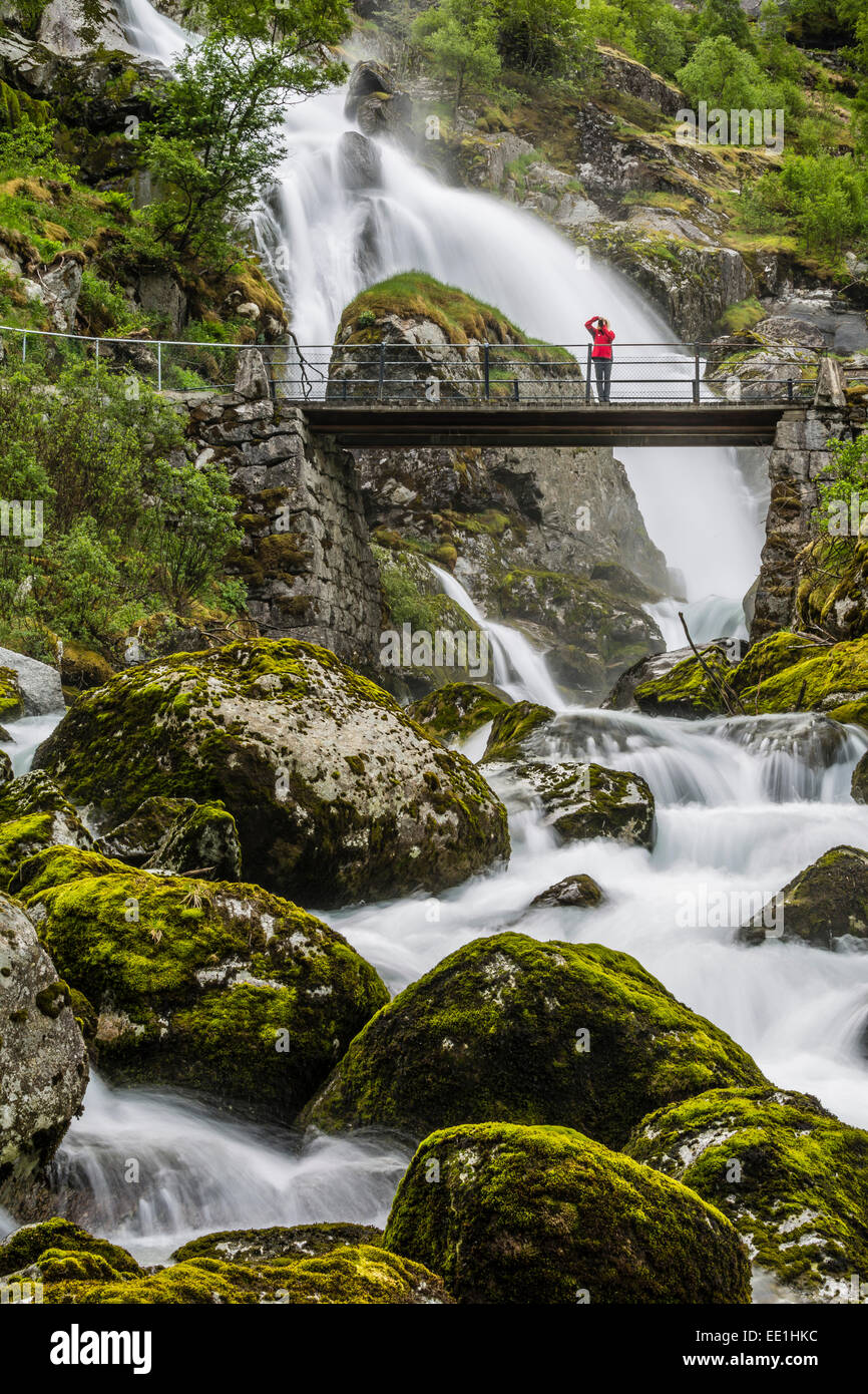 Velocidad de obturación lenta sedoso del agua del río y el puente de antaño como él fluye a lo largo de Briksdalen, Olden, Nordfjord, Noruega, Escandinavia Foto de stock