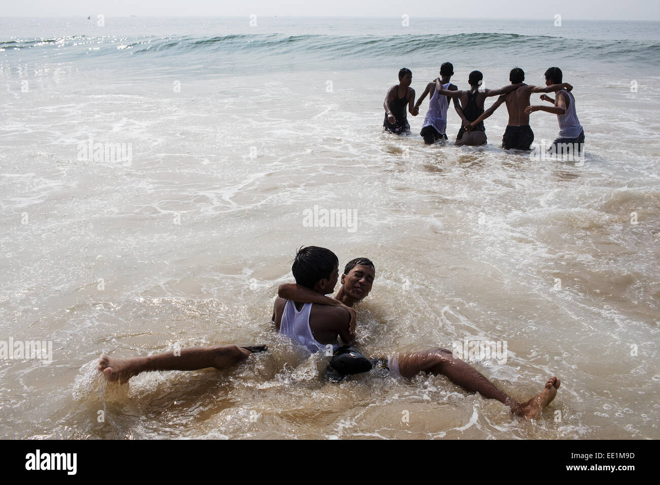 Un grupo de muchachos jugando en el agua del mar playa en Puri, Odisha, India Foto de stock