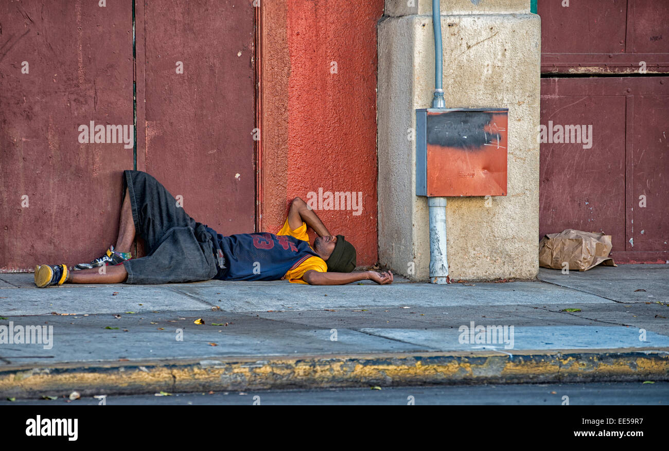 Hombre durmiendo en la acera junto al edificio, East Village, San Diego, California, EE.UU. Foto de stock