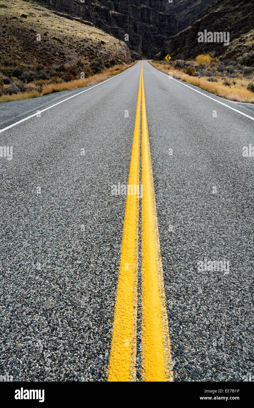 Detalle de la carretera con curvas y líneas amarillas dobles para guiar a los conductores de automóviles Foto de stock