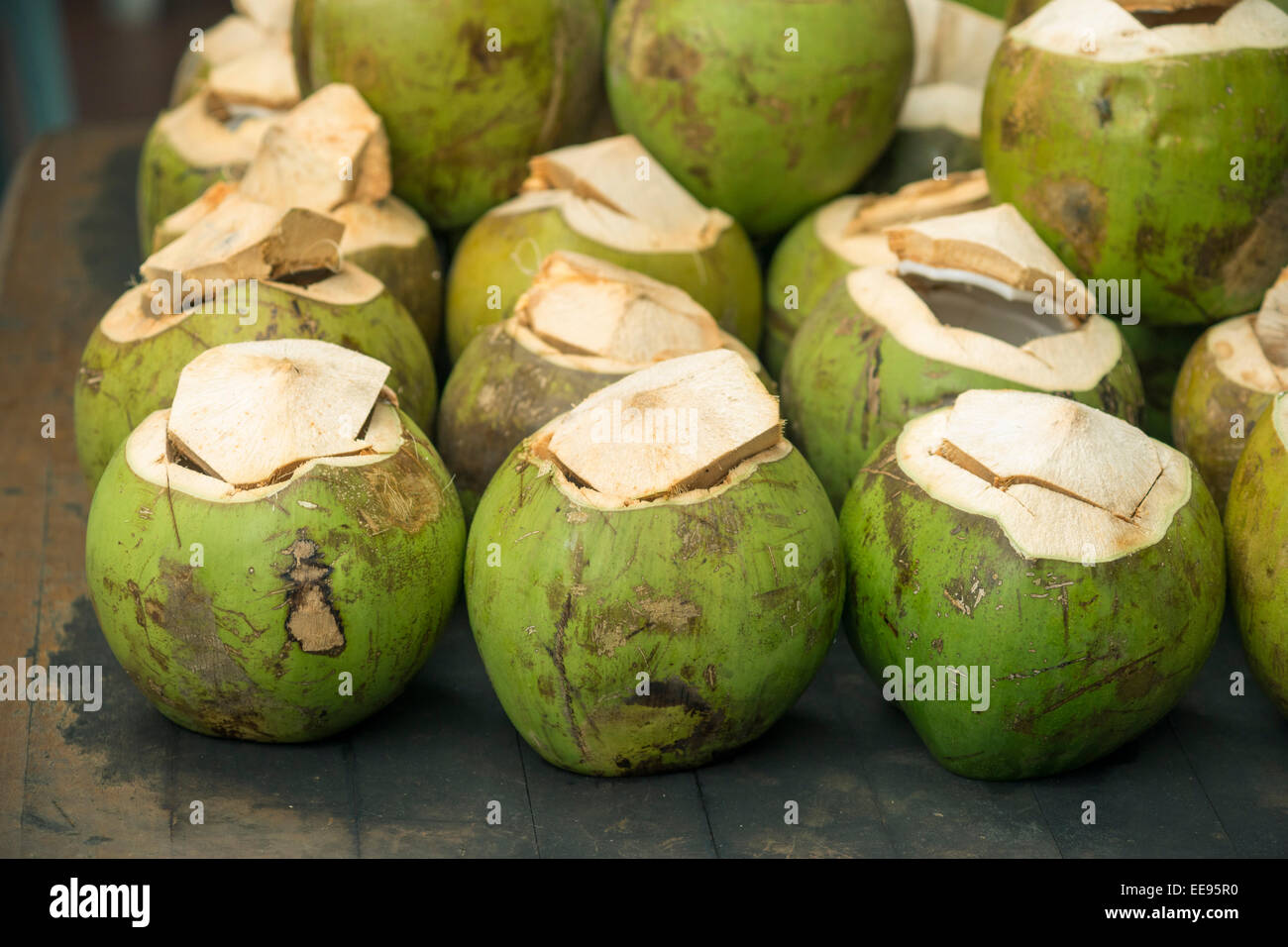 Muchos cocos verdes en tabla vintage con foco en la fila delantera Foto de stock