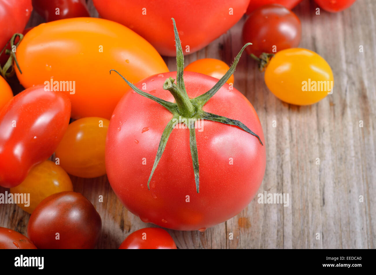 Colorido diferente tipo tomate de mesa de madera. Rojo, Amarillo, grandes y pequeños tomates. Verduras de verano. La comida mediterránea. Foto de stock