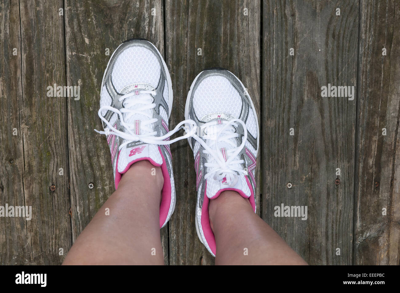 Pies con zapatillas sobre ellos de pie sobre una plataforma de madera. Los  zapatos tenis Fotografía de stock - Alamy