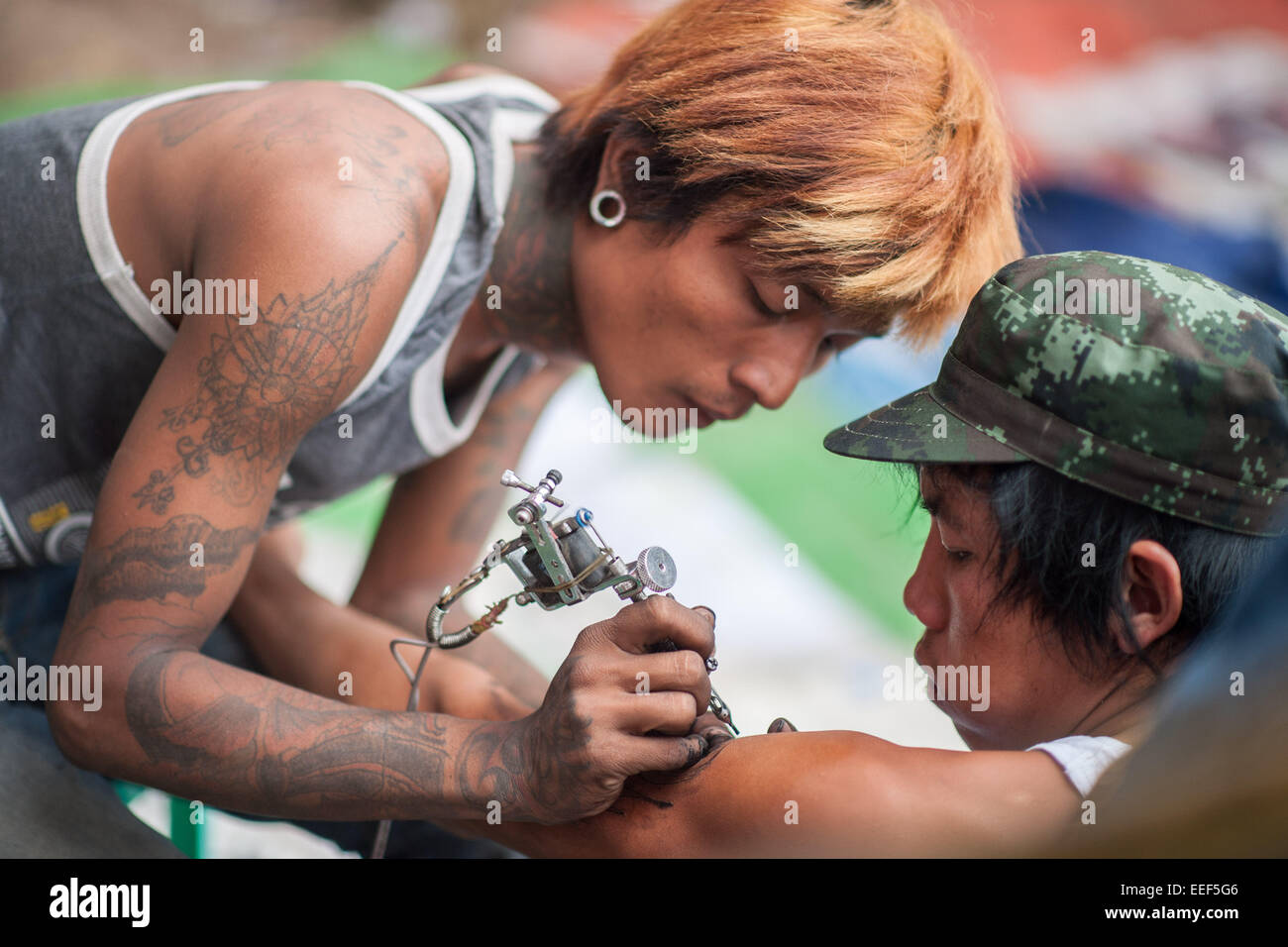 Artista dando un tatuaje en el 63º Aniversario del estado de Kayah, festival, Loikaw. Foto de stock