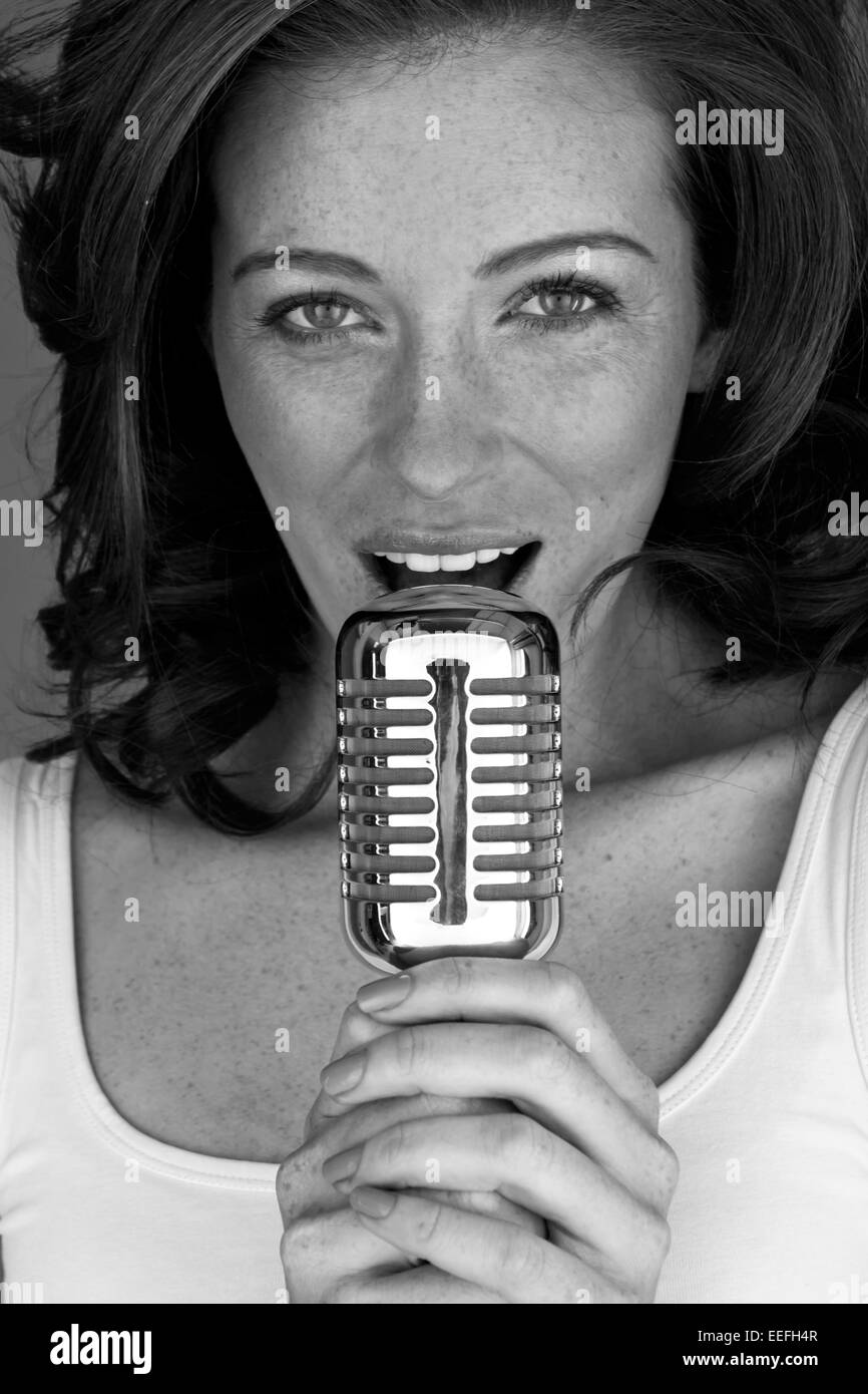 Retro pelirroja cantante con micrófono cantando su corazón. Foto de stock