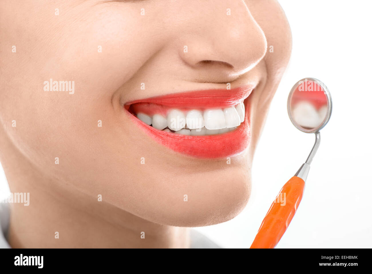 Mujer joven con espejo dental y amplia sonrisa saludable sobre fondo blanco. Foto de stock