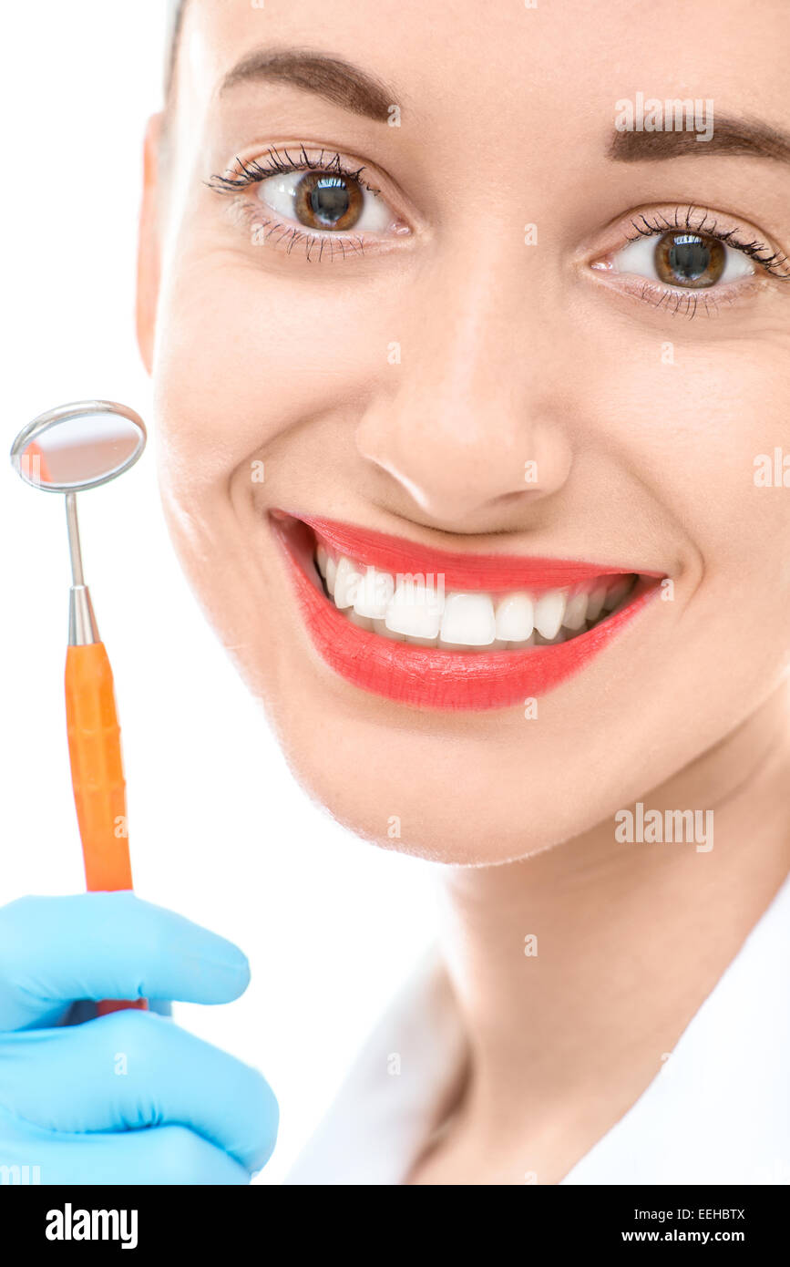 Mujer joven con espejo dental y amplia sonrisa saludable sobre fondo blanco. Foto de stock