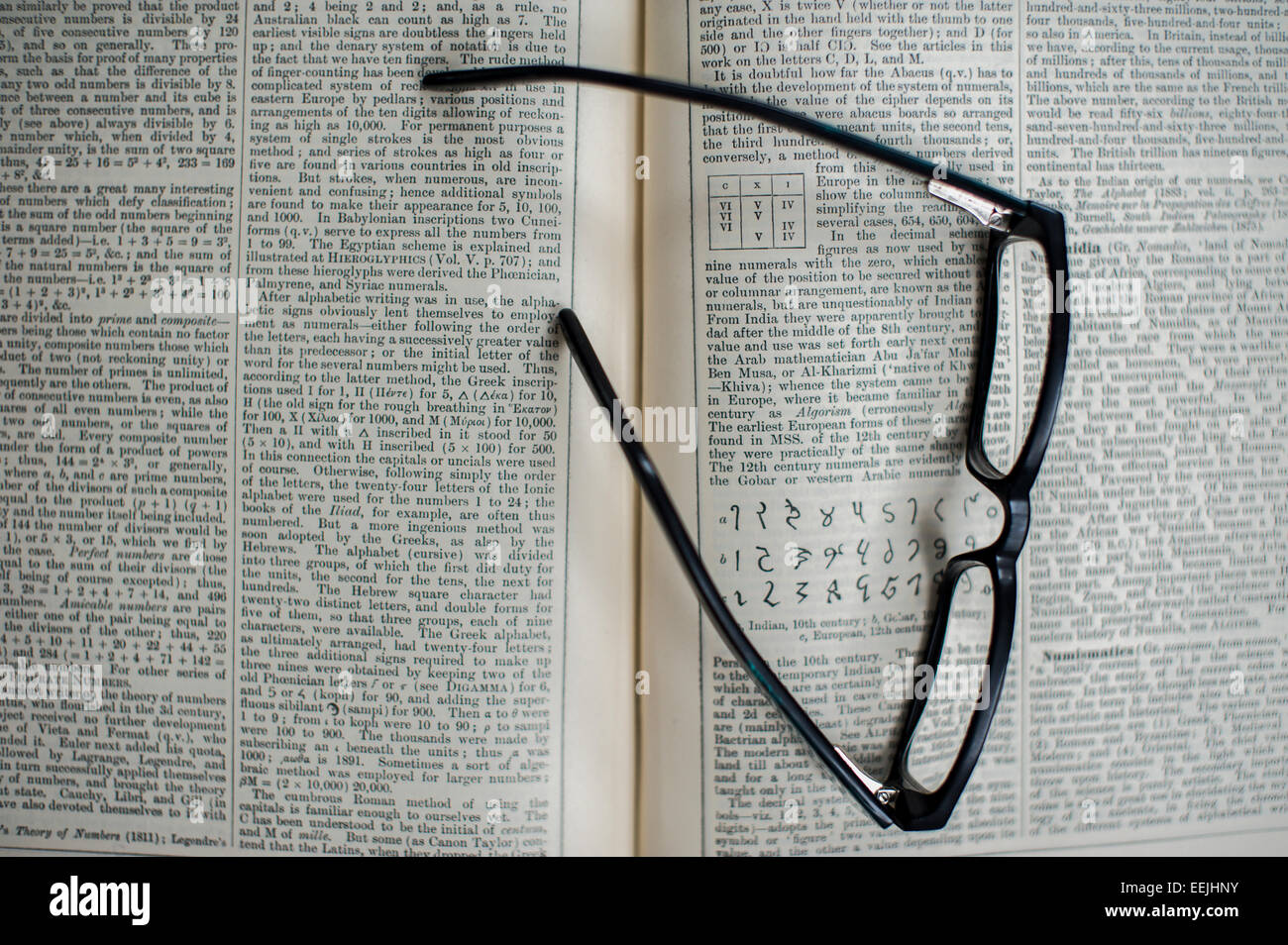 Par de gafas de lectura apoyada en una enciclopedia abierta Foto de stock