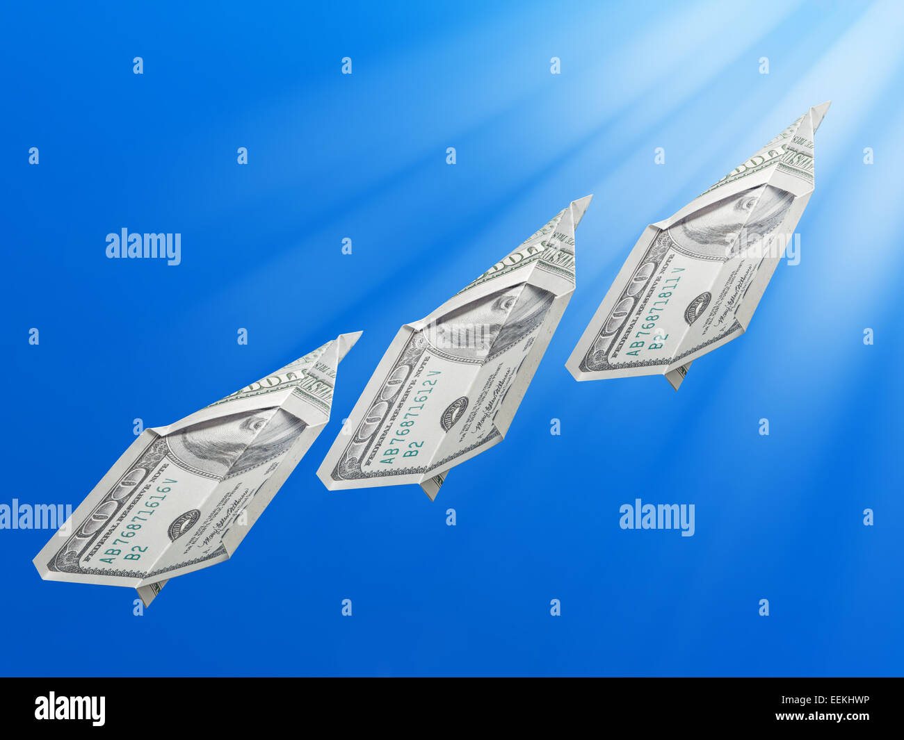 Billetes de cien dólares americanos plegada en aviones de juguete ascendiendo hacia el Sol Foto de stock