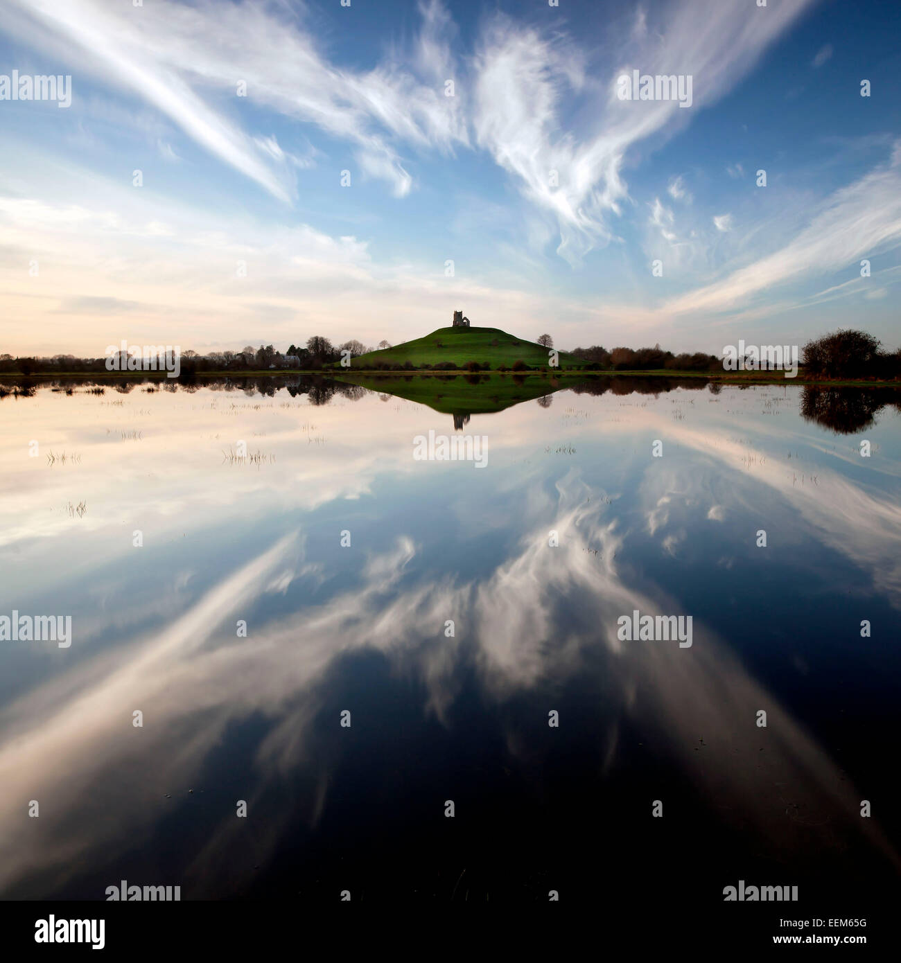 Reino Unido, Inglaterra, Somerset, niveles de Somerset, Hill y cielo nublado reflejando en el lago en calma Foto de stock