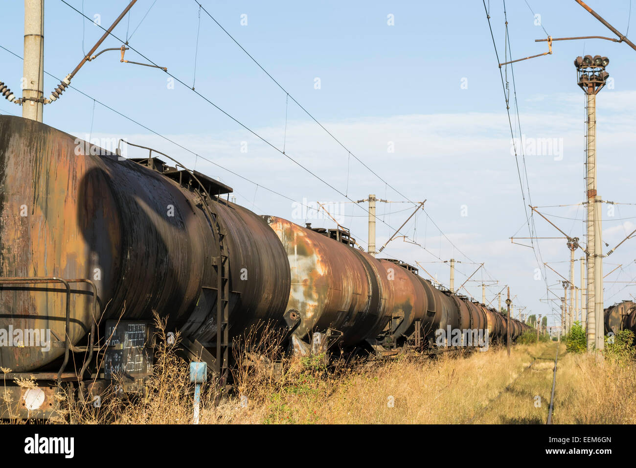 Larga línea de vagones de mercancías para el transporte de petróleo abandonados en vía férrea Foto de stock