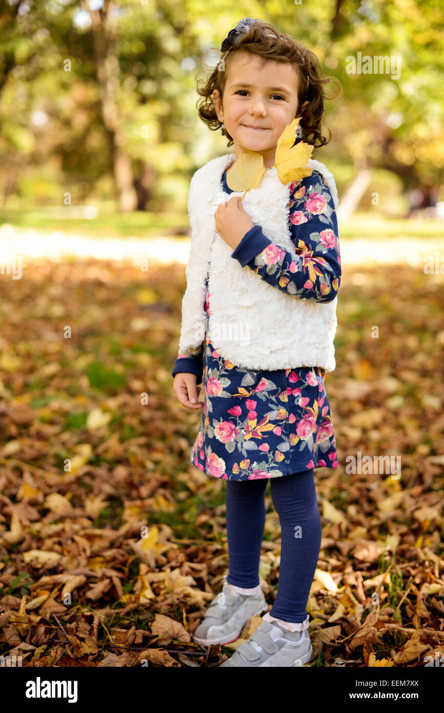 Retrato de niña (4-5) disfrutando y jugando con las hojas de otoño en el parque Foto de stock