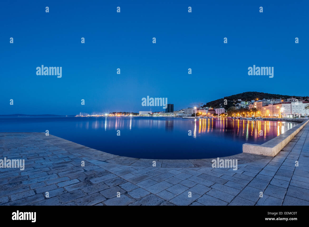 Waterfront acera, barcos iluminados y acoplar al anochecer, Split, Split, Croacia Foto de stock