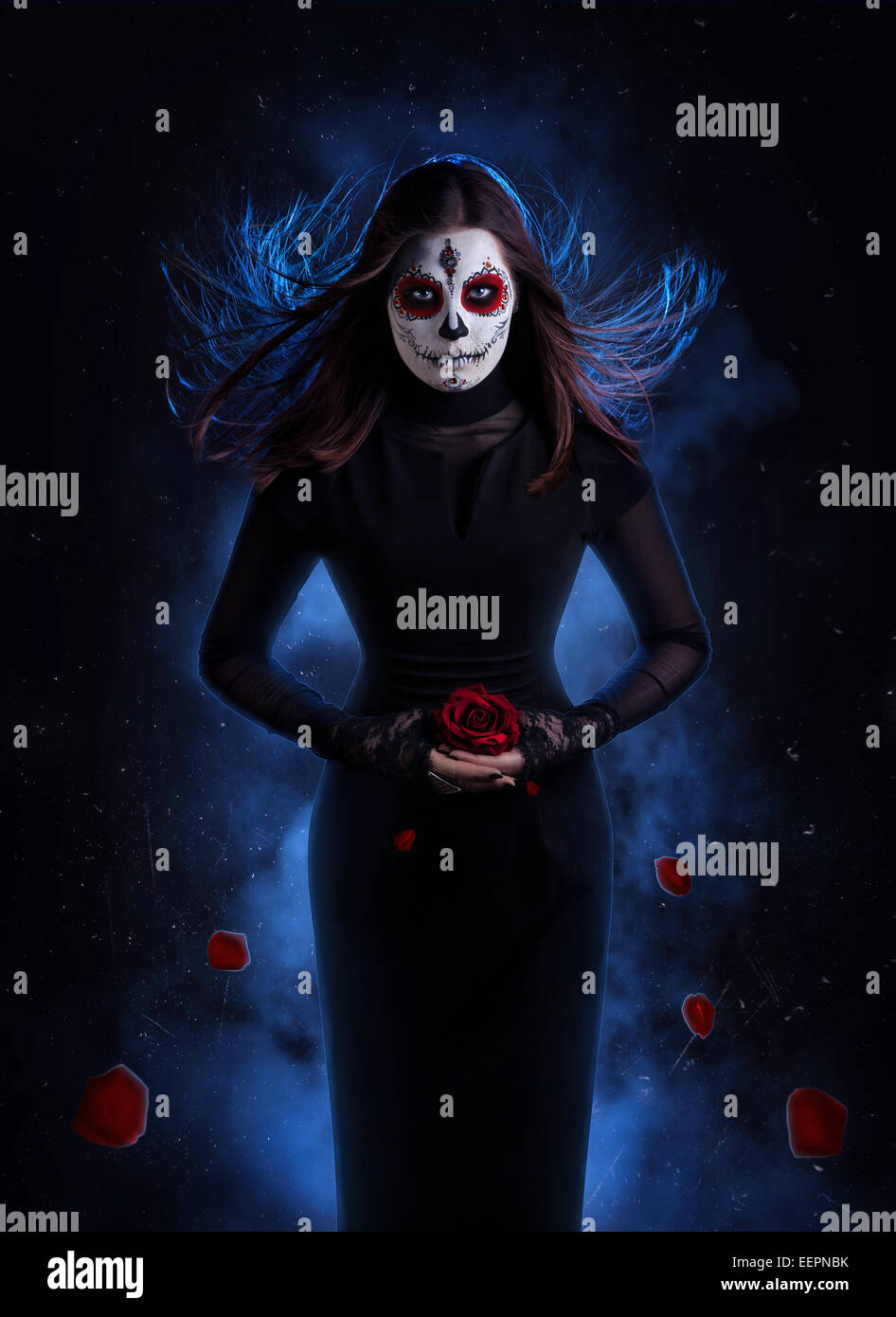 Mujer de vestido negro con calaveras de azúcar holding de maquillaje con  caída de pétalos de rosas rojas en fondo oscuro Fotografía de stock - Alamy