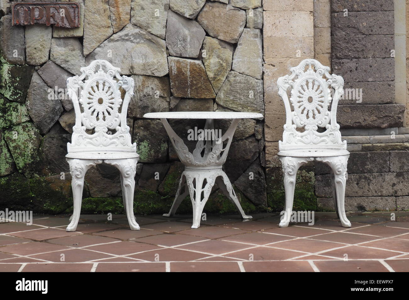 Al aire libre, de hierro fundido pintado blanco una mesa y dos sillas. Foto de stock