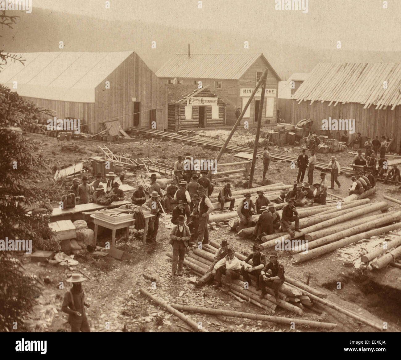 Descansando, Dawson City - vista de pájaro de hombres sentados en los registros y en permanente construcción con vista del restaurante "Eldorado" y el "iners Home' en el fondo. Foto de stock