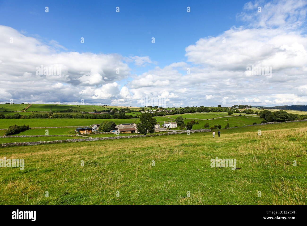 2 personas caminando bajo skys azul y las nubes blancas en verano cerca de pradera lugar Grange sobre Haddon Derbyshire, Inglaterra Foto de stock