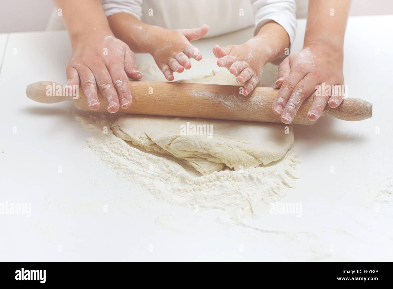 Madre e hija manos amasar la pasta sobre la mesa. Foto de stock
