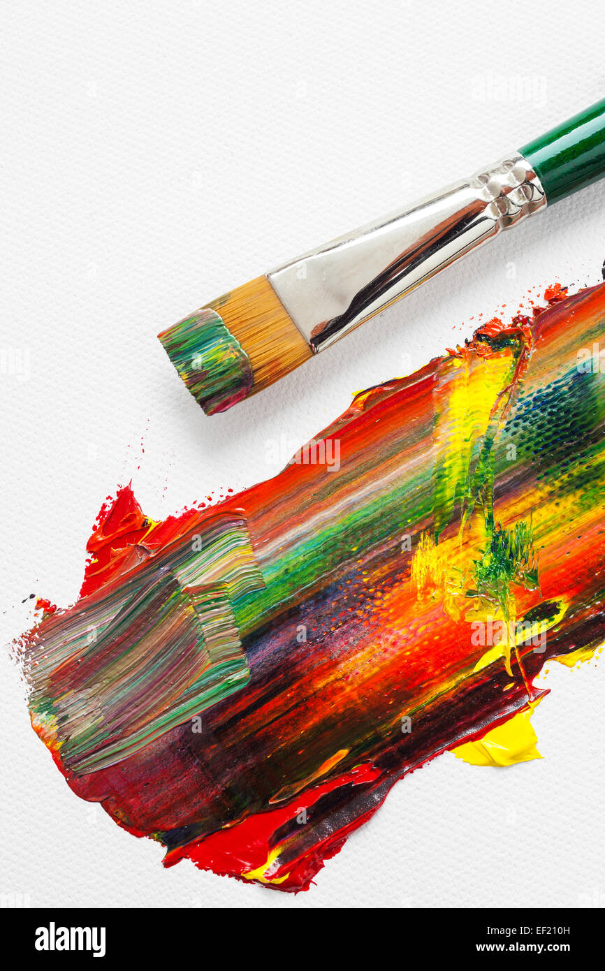 Pincel y mezclado rainbow pinturas al óleo sobre lienzo de artista blanco Foto de stock