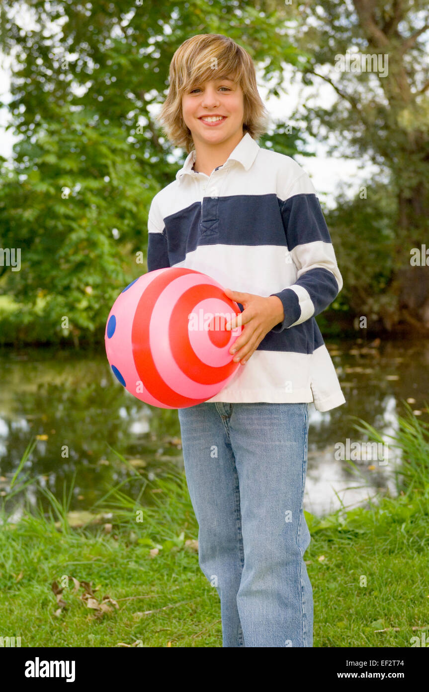 Joven sosteniendo un balón de playa Foto de stock