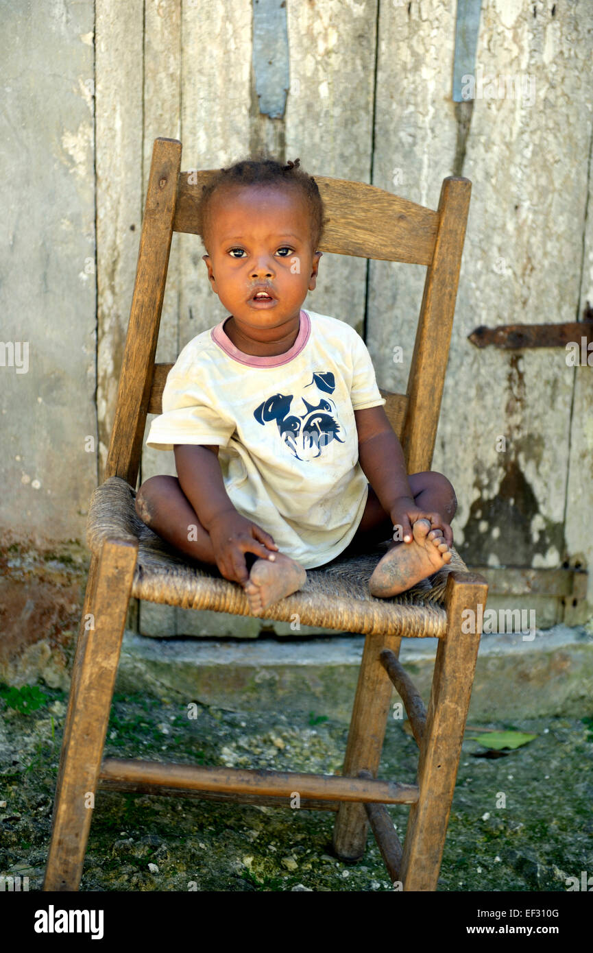 Chico sentado en una silla inclinada, la conge, Sud-Est (Departamento, Haití Foto de stock