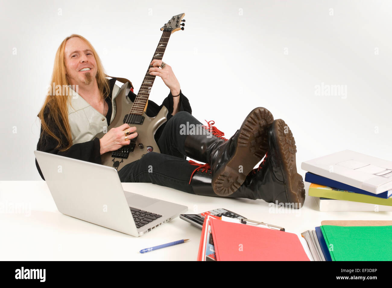 El guitarrista de pelo largo sentado en el escritorio Foto de stock