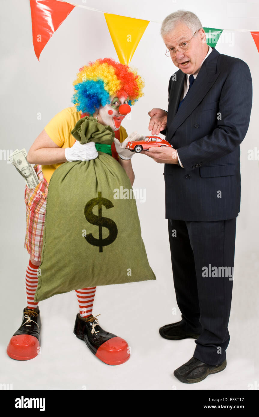 Payaso sosteniendo una bolsa de dinero al lado de un vendedor de coches Foto de stock
