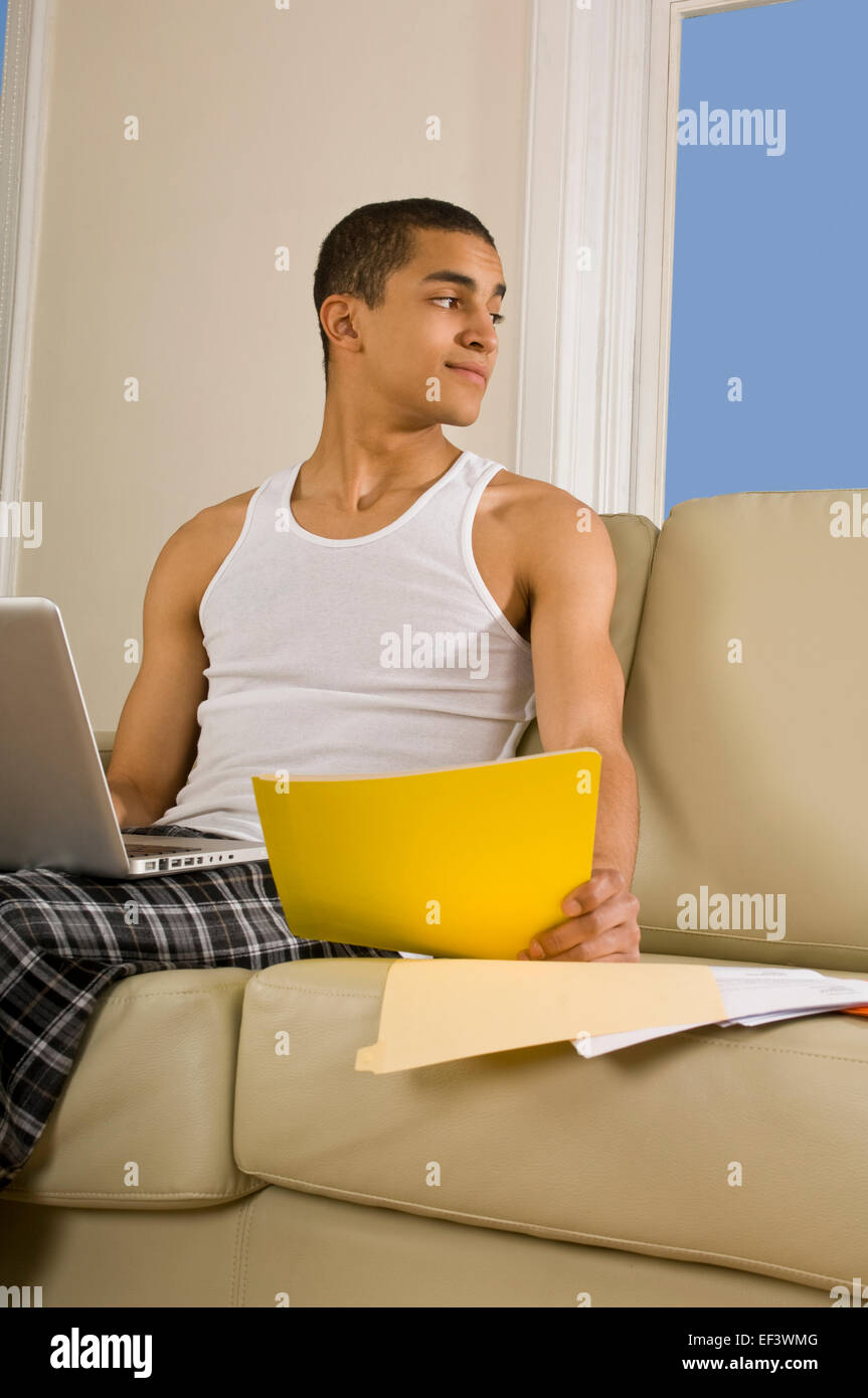 El hombre soñar despierto mientras está sentado en el sofá con el portátil Foto de stock
