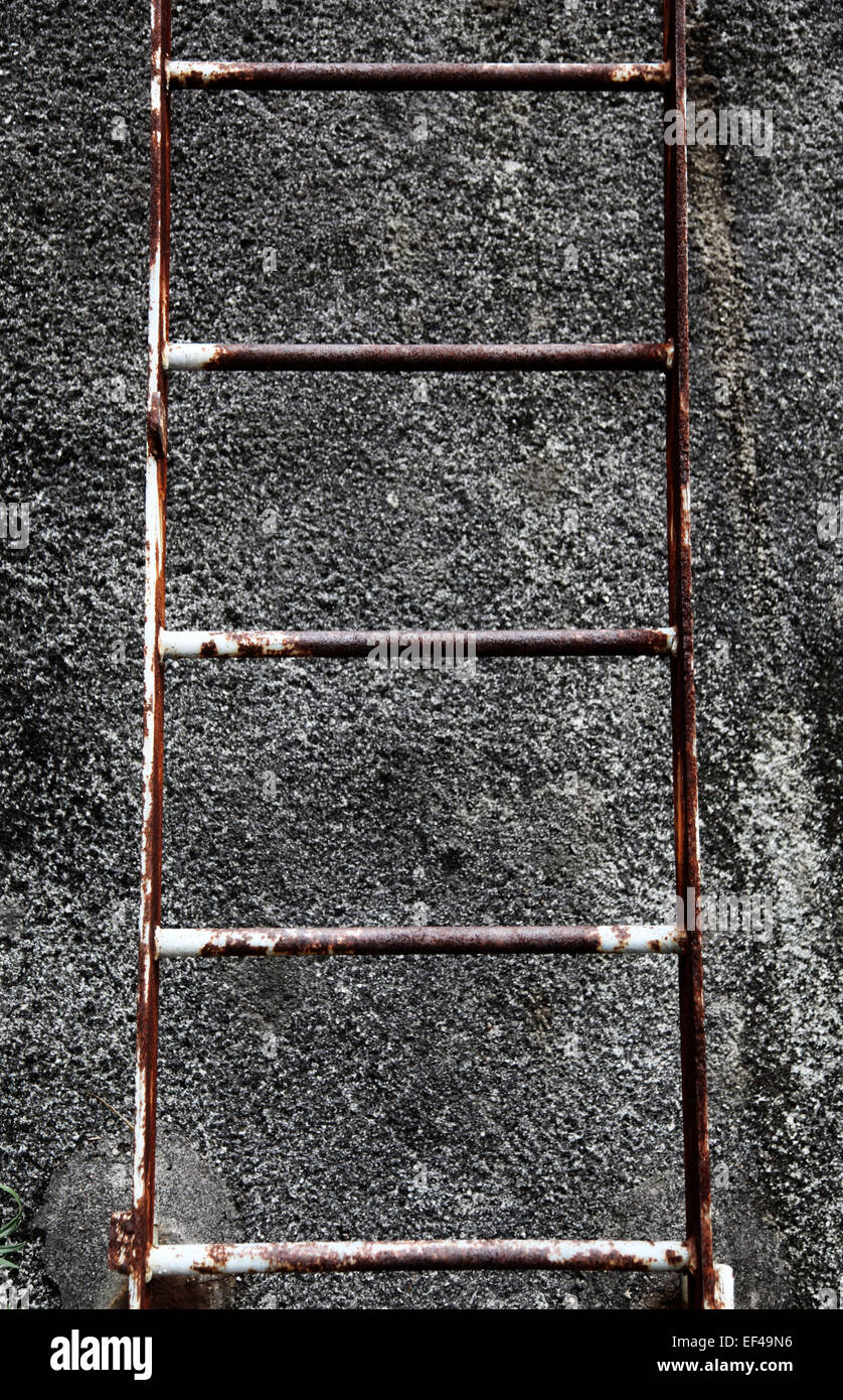 Esta es una foto de un detalle de una escalera de acero oxidado que está contra una pared de hormigón áspero Foto de stock