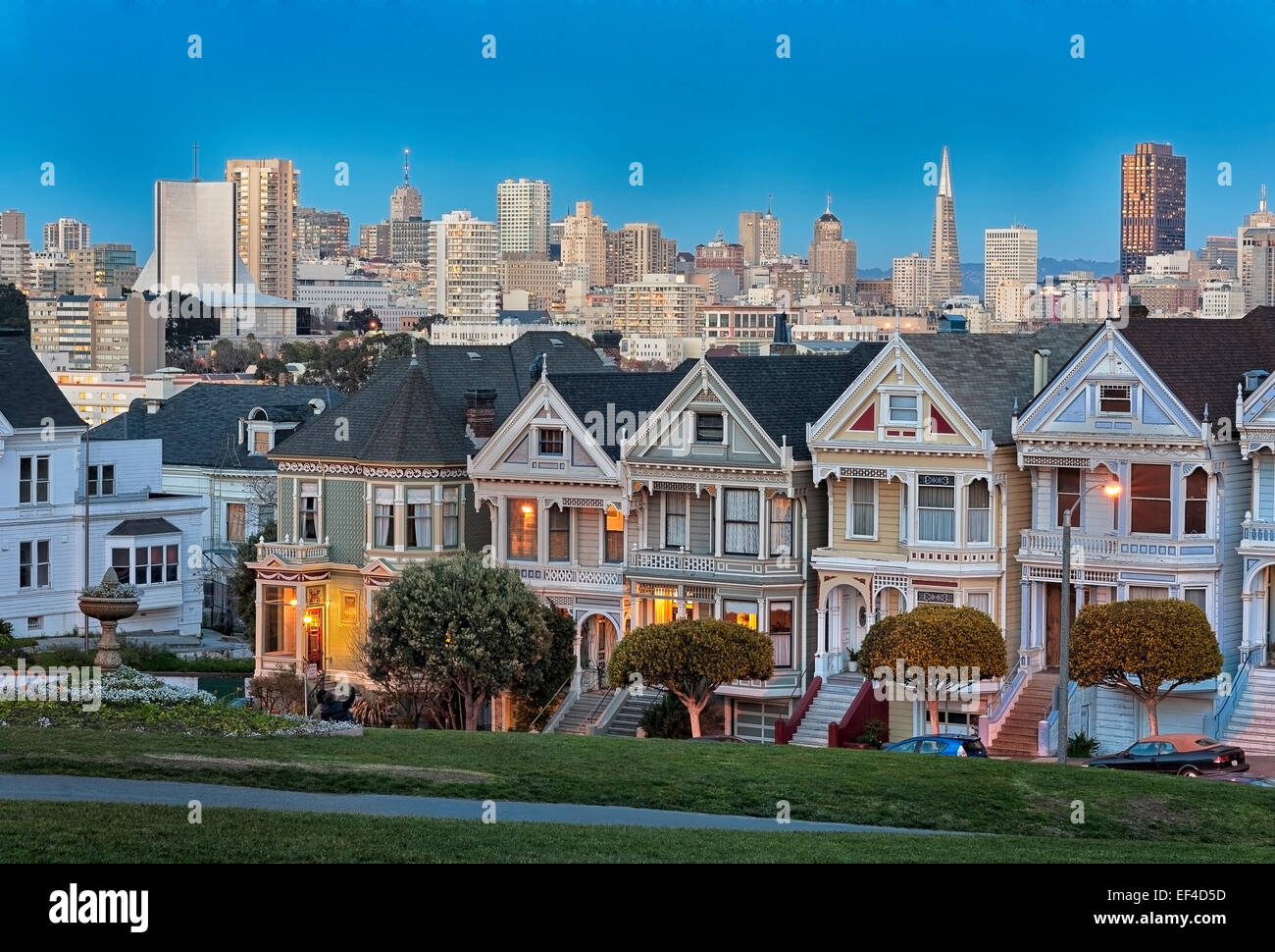 La icónica "Damas Pintadas" con el centro de San Francisco, detrás del horizonte fotografiados después del atardecer desde Alamo Square en San Francisco, California. Foto de stock