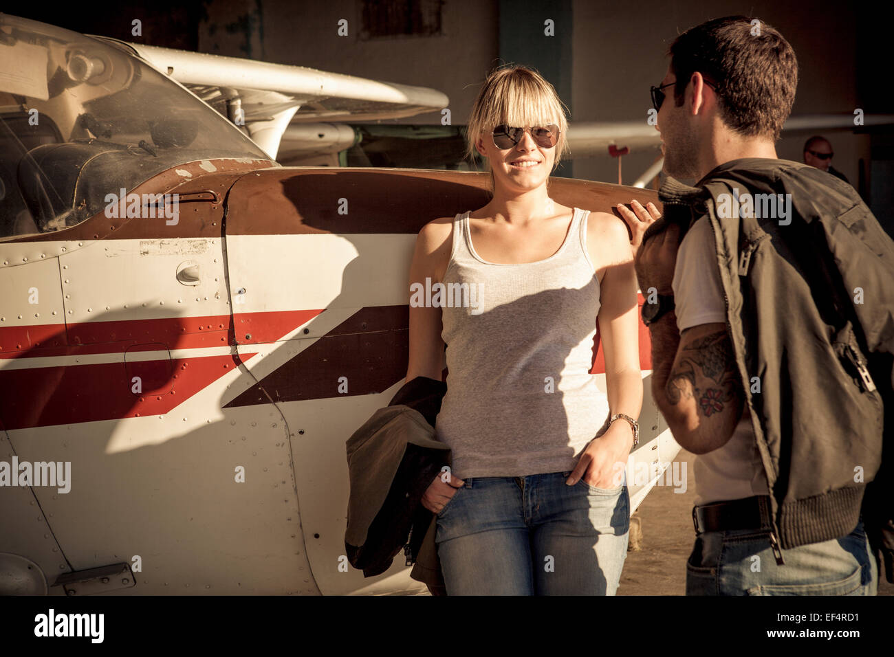 Pareja joven apoyándose contra el avión de hélice Foto de stock