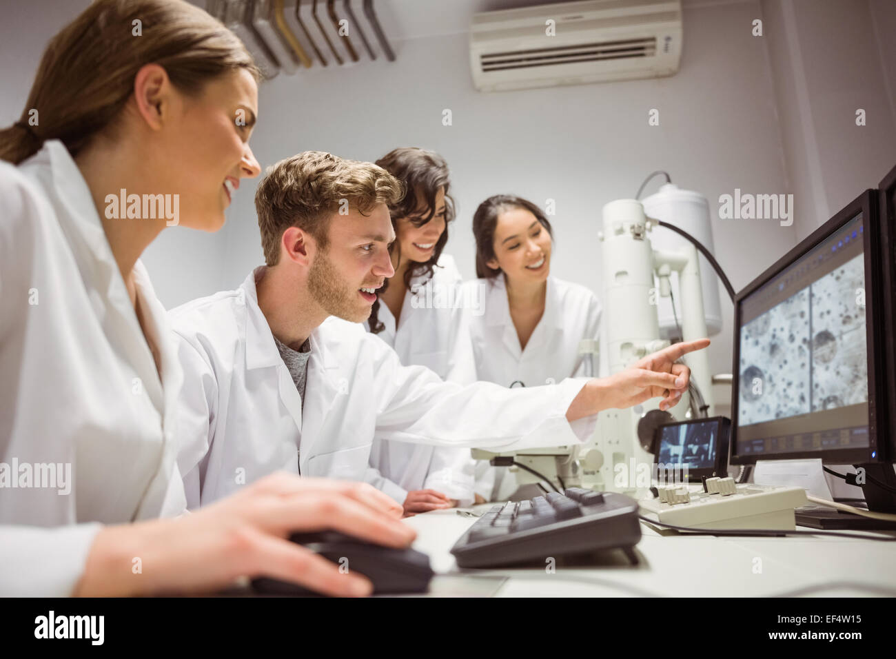Los estudiantes de ciencias mirando imagen microscópica en el equipo Foto de stock