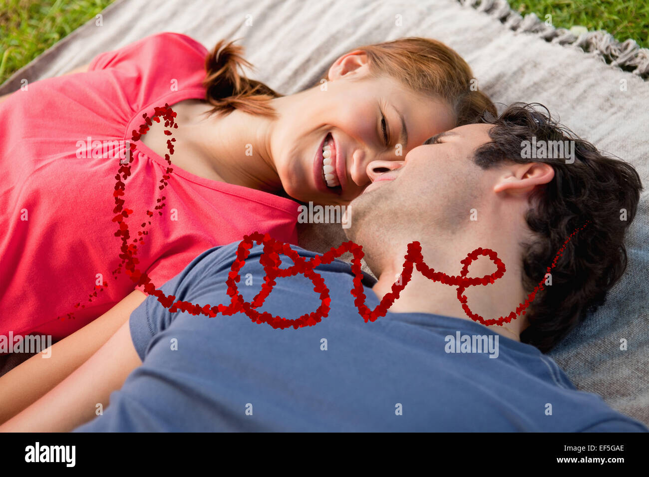Imagen compuesta de mujer sonriendo mientras yacía junto a su amigo en una colcha Foto de stock