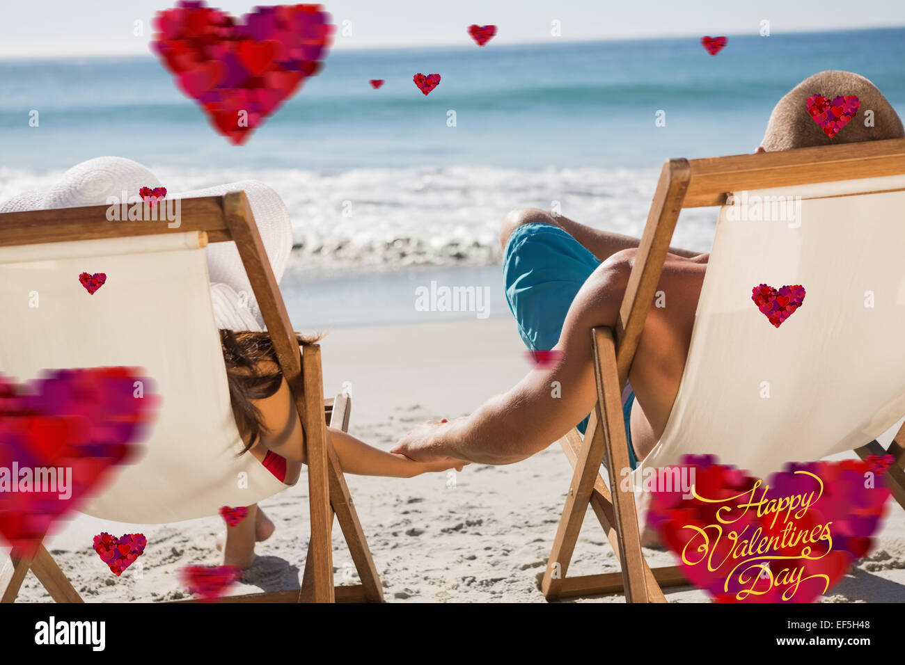 Imagen compuesta de linda pareja tomados de las manos mientras yacían en sus tumbonas Foto de stock